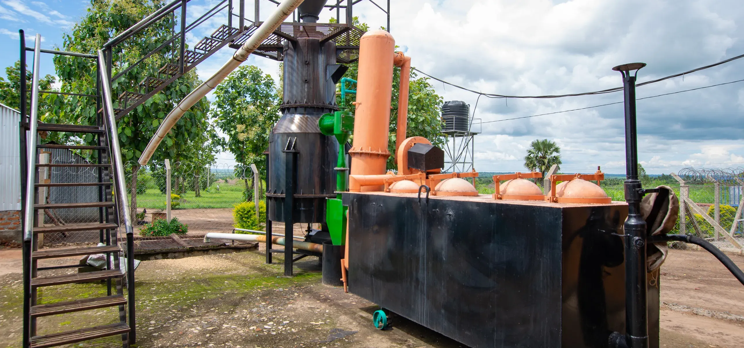 The gasifier's cyclone separators and sealed char collection tank standing in open ground at Got Ngur