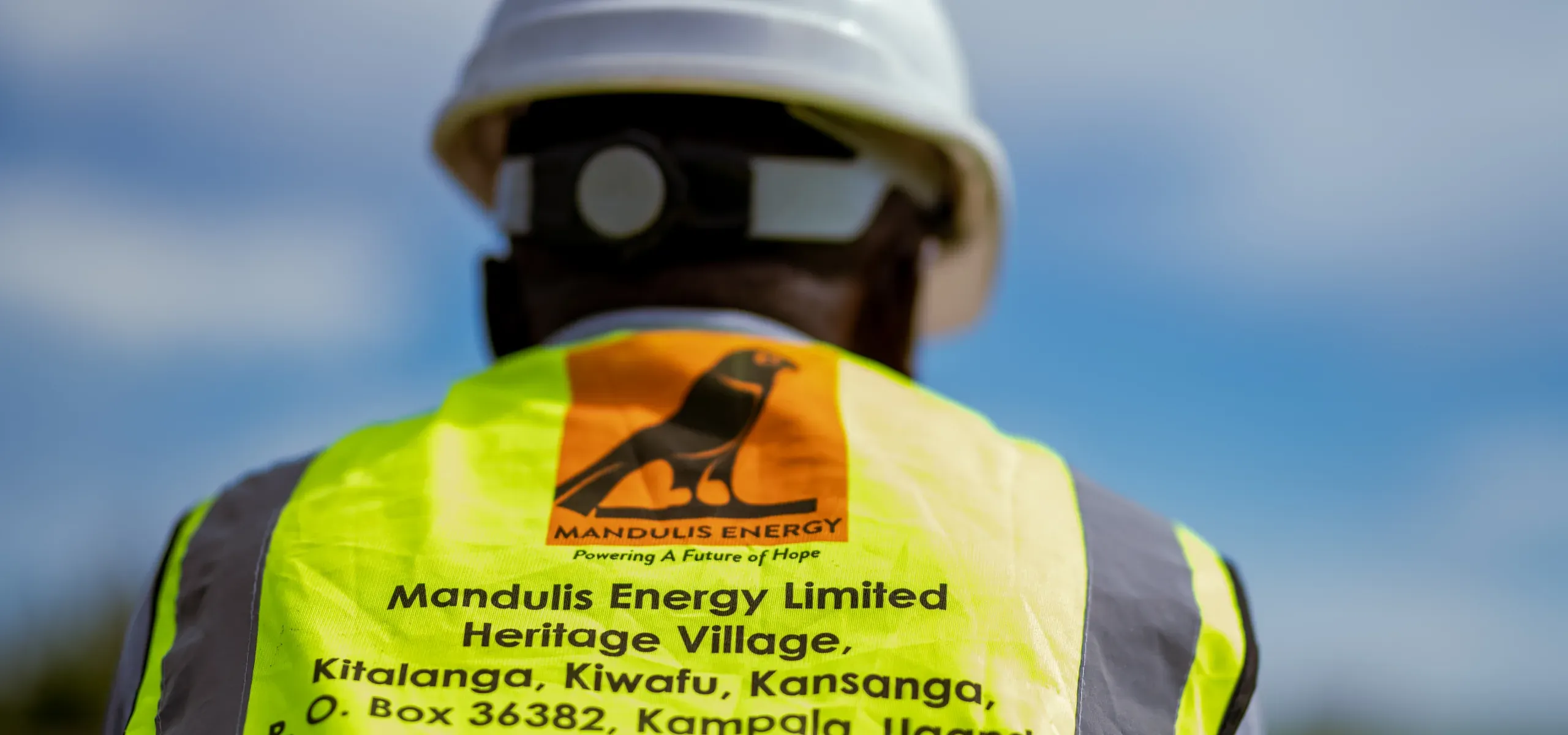The back of a Mandulis Energy branded work vest, worn at a community gathering