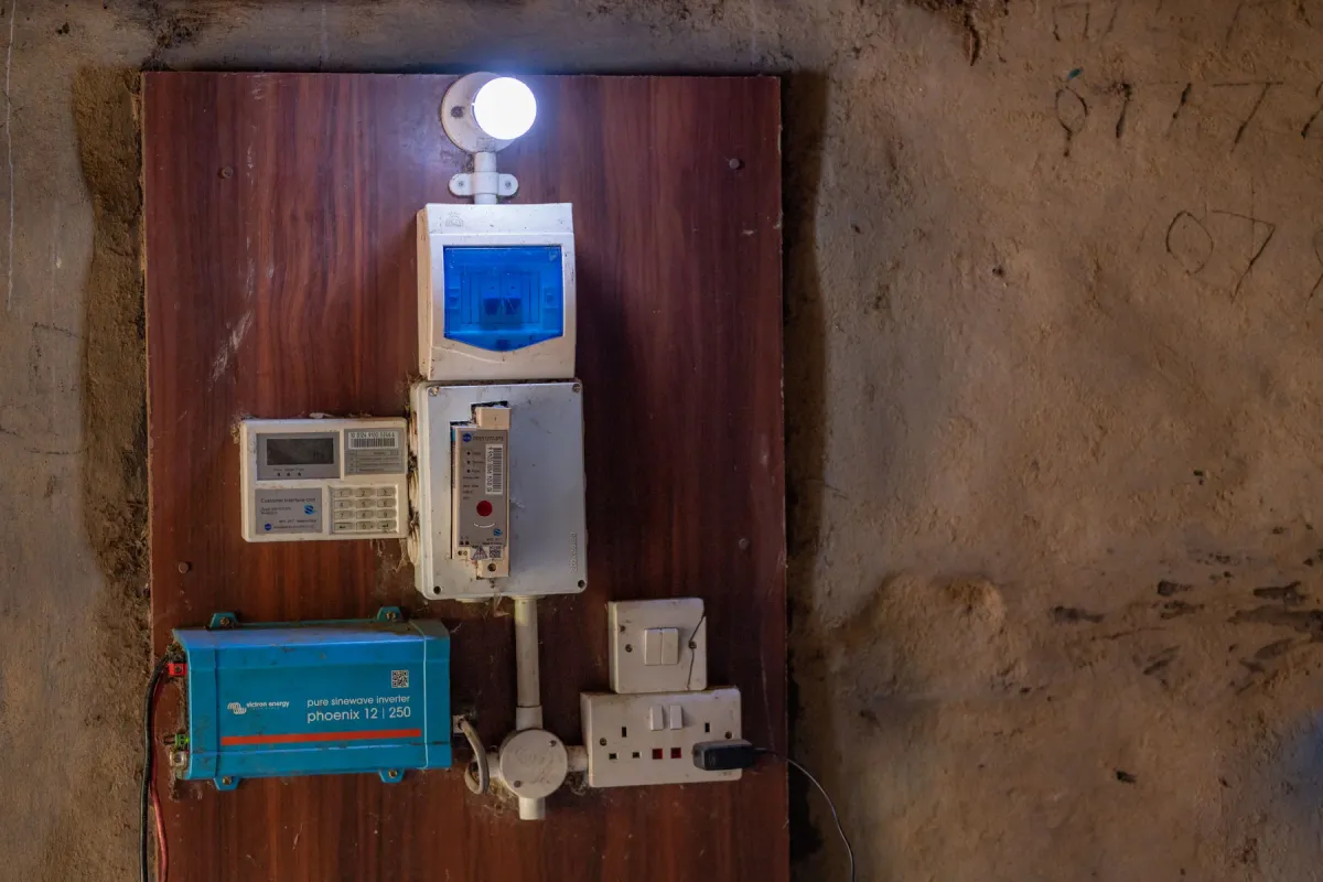 A customer inside her home, lit by electricity from the mini grid