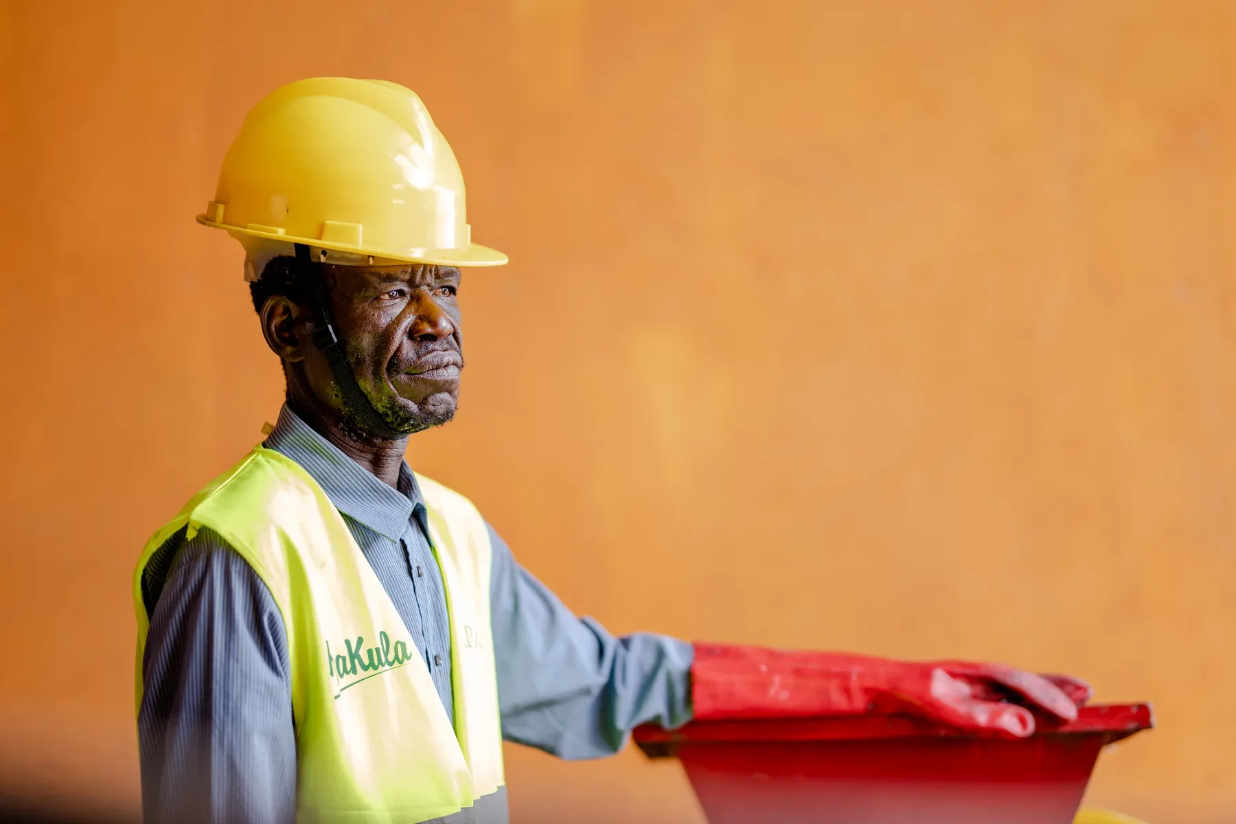 A plant operator in a hard hat and protective gloves at the material handling hopper