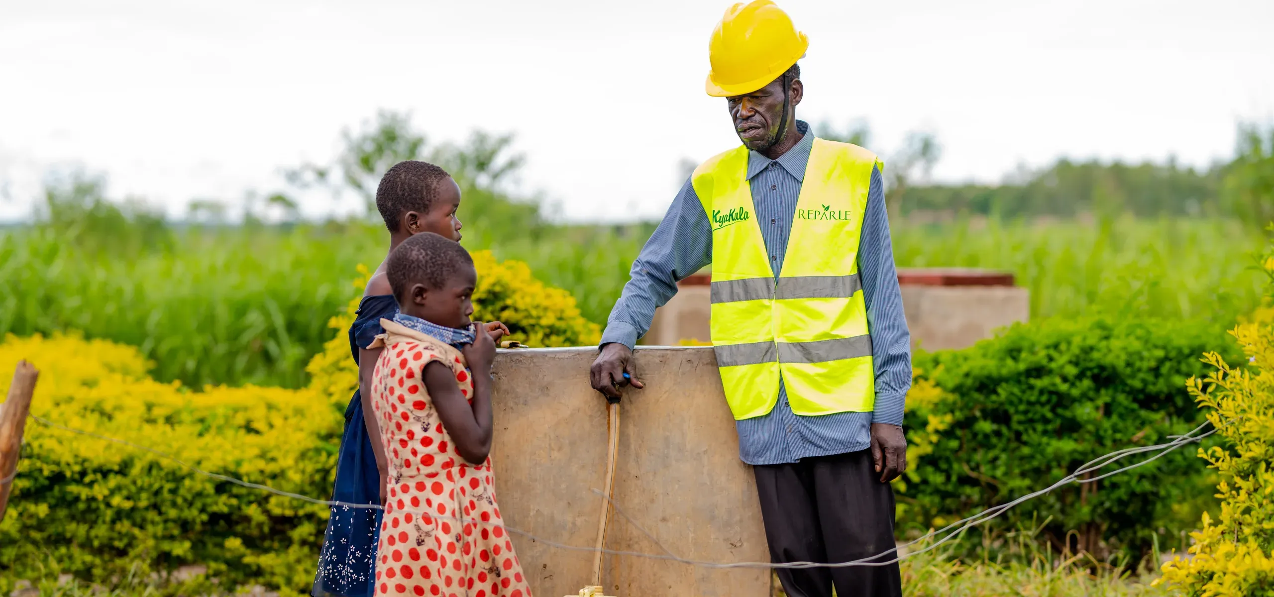 A project worker and two children at a water collection point near Got Ngur